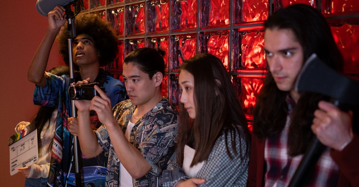 Grupo de adolescentes ensayando una escena teatral sobre un escenario con telón de fondo